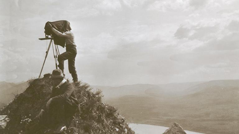 Photographer on the tip of a mountain taking a photo using a large format camera.