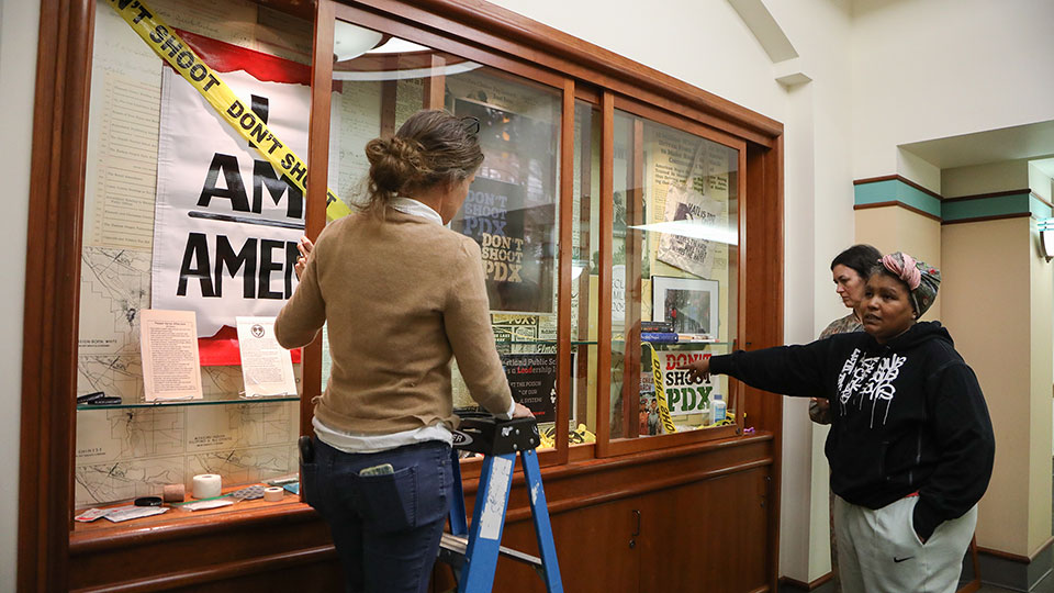 Danielle Mericle, visual materials curator (left) with Teressa Raiford from Don't Shoot Portland and Tiffany Harker from Holding Contempory Gallery installing the "Archives for Black Lives" exhibition in Knight Library in Eugene