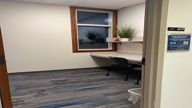 Graduate study room 417 of Knight Library. Door open and a chair with desk and small plant on a shelf inside of the room