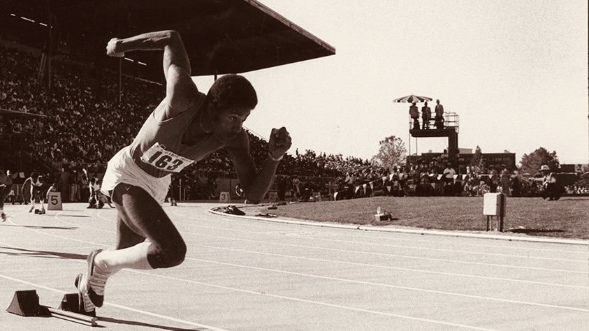 Historic photo of a Black male runner sprinting from starting blocks at Hayward Field.