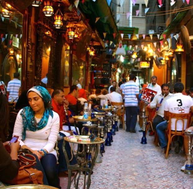 a busy cairo street full of outdoor dining tables.