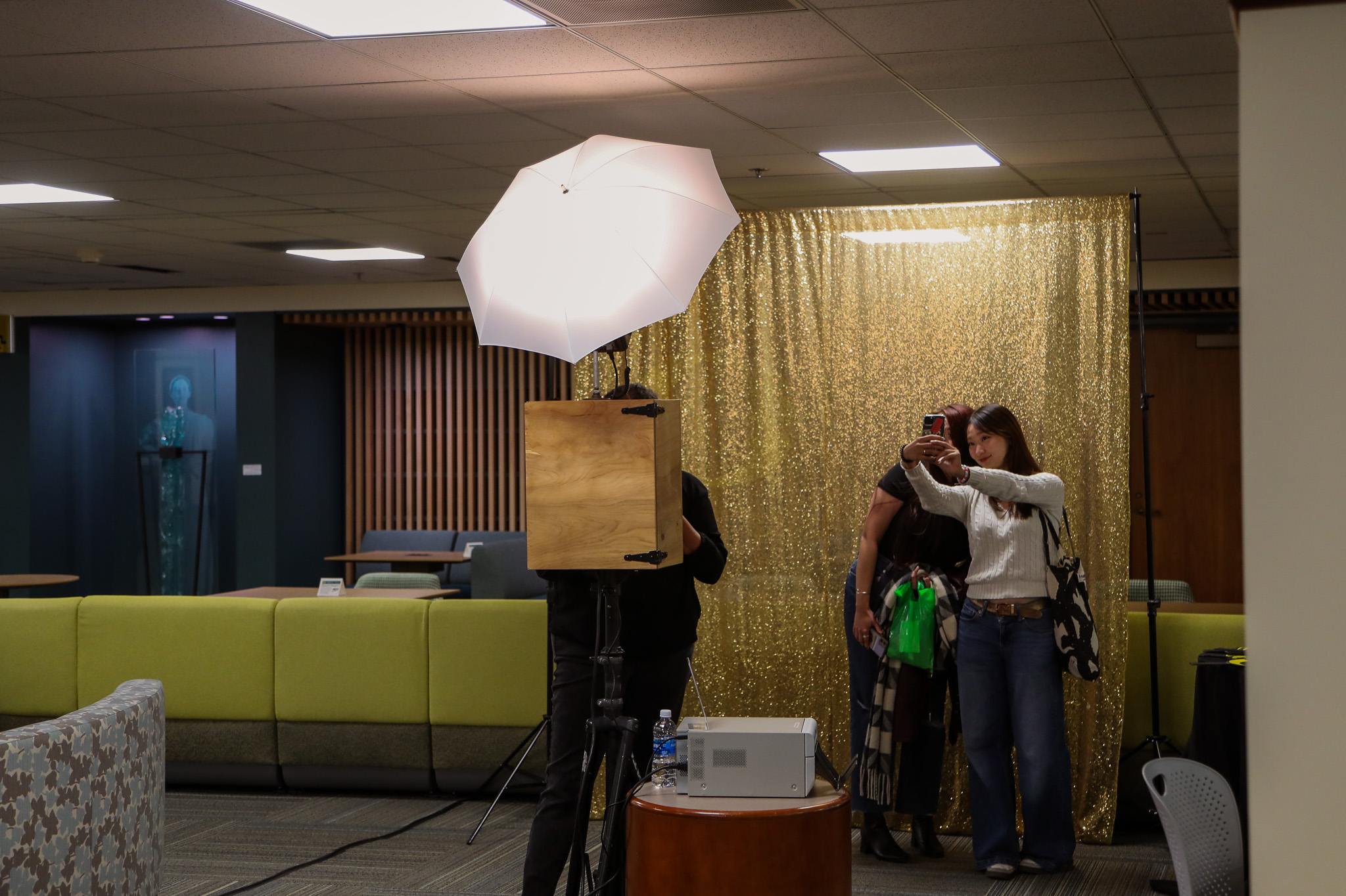 Young woman taking a cellphone selfie while standing in the photo booth.