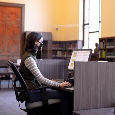 Lauren Goss sitting at a computer in the Special Collection's reading room