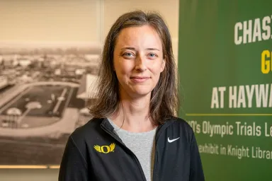 Lauren Goss, athletics archivist, in front of the Chasing Gold exhibit banner