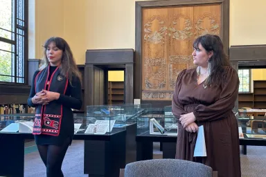 Two women stand in a brightly lit reading room.