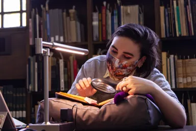 Person looking at book with magnifying glass