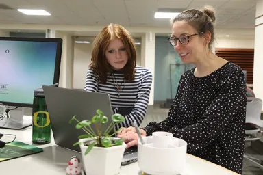 Two people at a desk looking at a computer screen