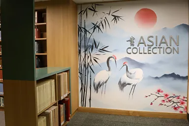 The new mural in the Asian Collections section on the second floor of Knight Library depicts two cranes, a red sun, and bamboo against a backdrop of mountains and sky.