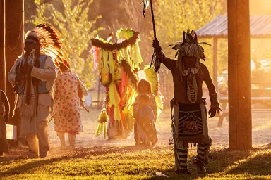 Photo, courtesy of Joe Whittle from his Landback project, depicts Indigenous dancers and children watching them.