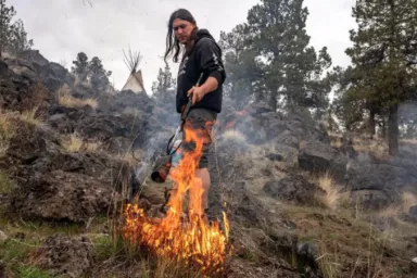 Yurok Nation member Chah-pekw Jonny burns dead grass to prepare the land for native seed planting at Sakari Farms in March 2022. Tribes such as the Yurok have long utilized fire as a tool for maintaining productive and healthy forest and grassland ecosystems.