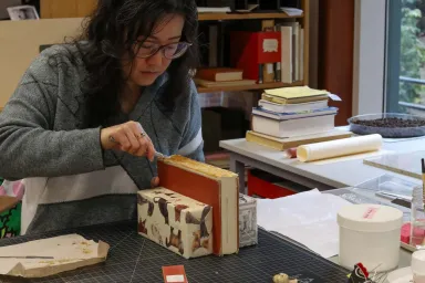 Victoria Wong repairing the spine of an old book in the UO Libraries&#039; Beach Conservation Lab