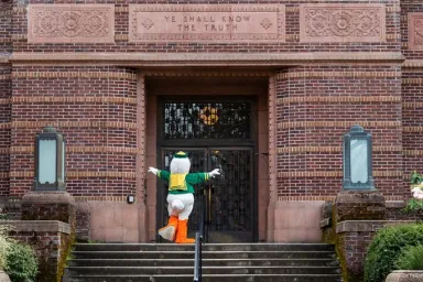 The Oregon Duck climbing the stairs to the entrance to Knight Library.