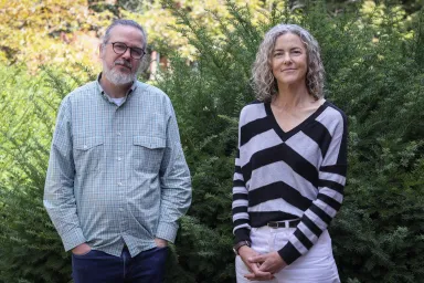 Justin Spence and Elizabeth Peterson standing against a backdrop of campus greenery.
