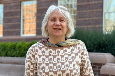 Portrait photo of Heghine Hakobyan standing outside Knight Library. She is wearing a patterned sweater and scarf.