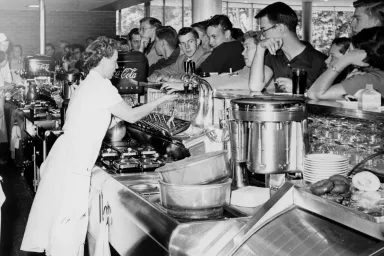 Black-and-white photo of workers serving students at the snack bar in the EMU fishbowl, circa 1950s or early 1960s..