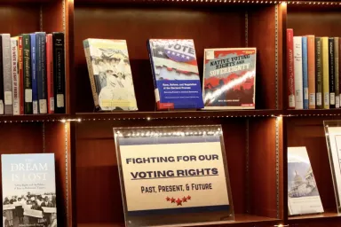 Display bookshelves in Knight Library hold many books and a sign that reads, &quot;Fighting for Our Voting Rights.&quot;