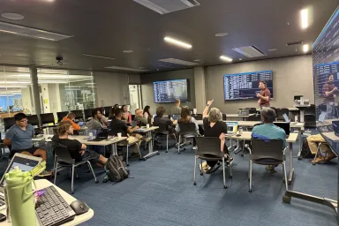 Standing at the front of a classroom, William Winter of RACS leads an HPC workshop session.