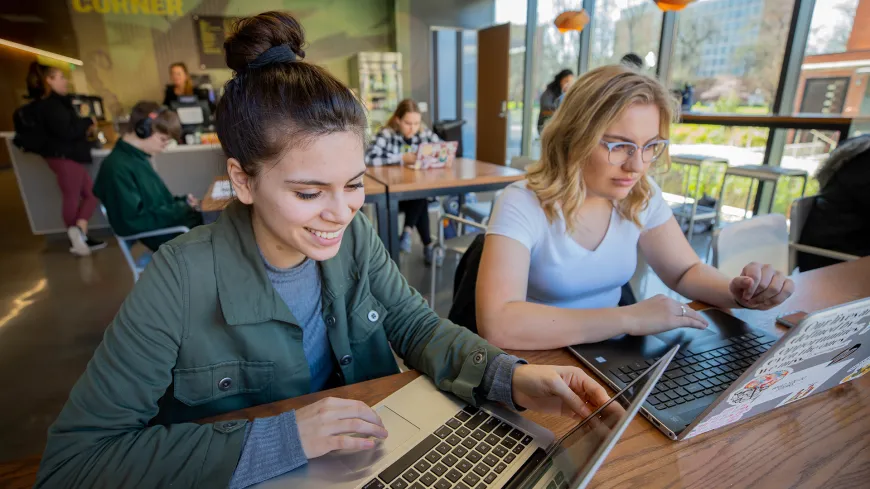 two students working on laptops