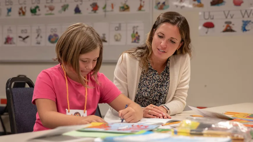 a young child working at a desk with a teacher