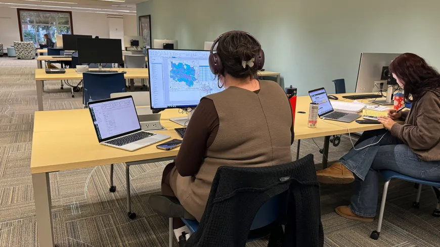 Two people at a desk looking at computer screens