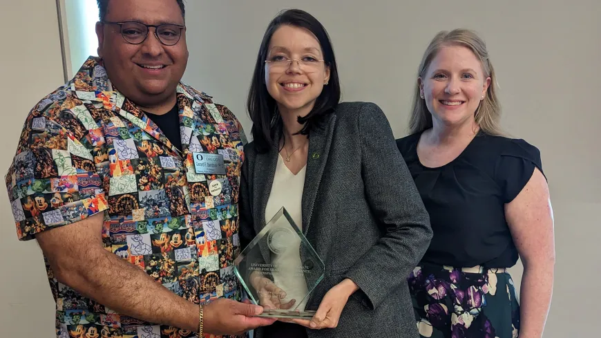 three people looking at the camera and holding an award