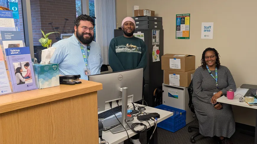 three people in an office behind desks