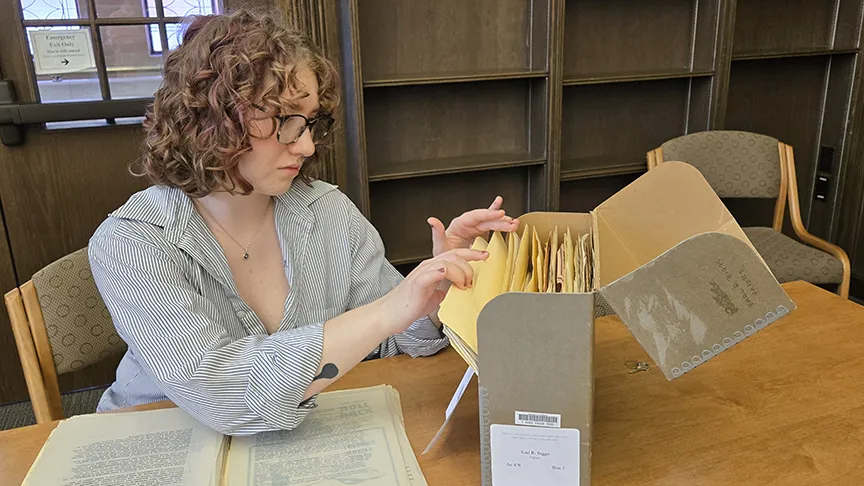 Hailey Battrick examining a box of collection materials in the Special Collections and University Archives.
