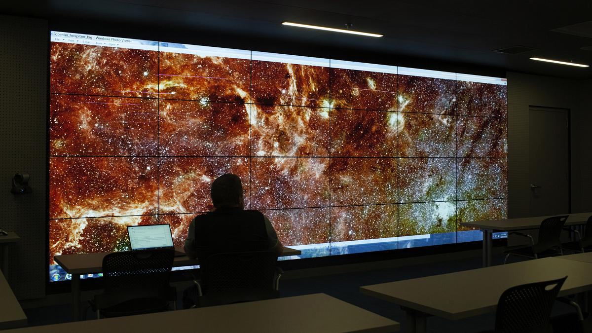 silhouette of a person looking at an image of space on the visualization lab screen