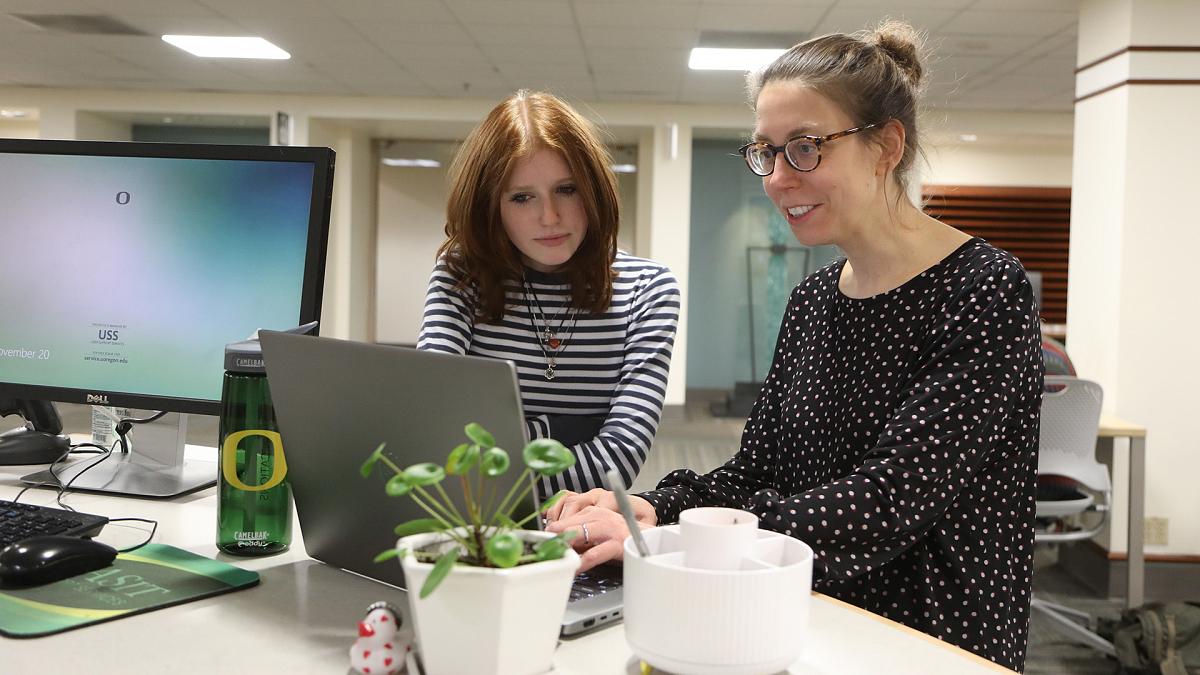 A student and a librarian looking at a laptop together