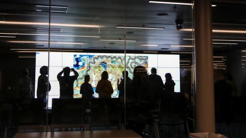 the silhouette of a group of people in front of a large screen