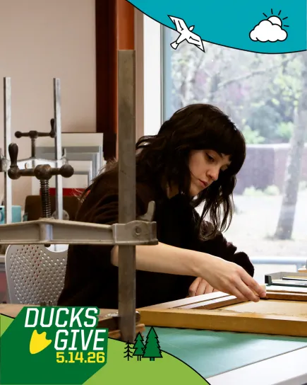 Student worker cleaning the back on a canvas painting on a bench in the Beach Conservation Lab