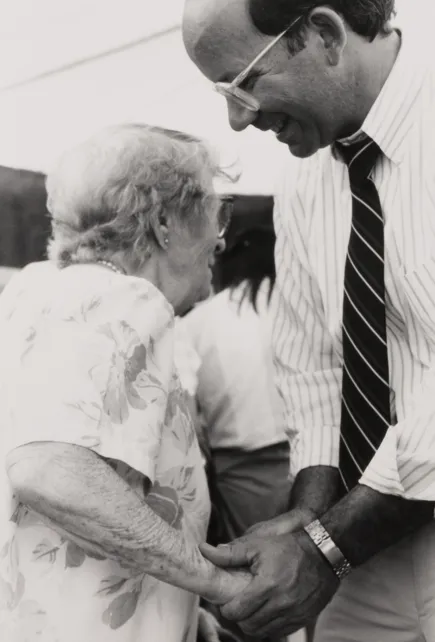 Peter DeFazio holding the hand of an elderly woman.