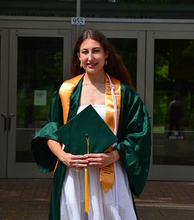 Chloe Thomae wearing graduation gown, holding mortarboard hat.