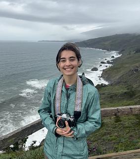 Mia Hanson holding a camera at the Oregon Coast.