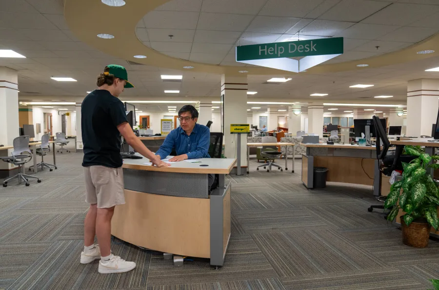 A student standing at the Knight Library help desk