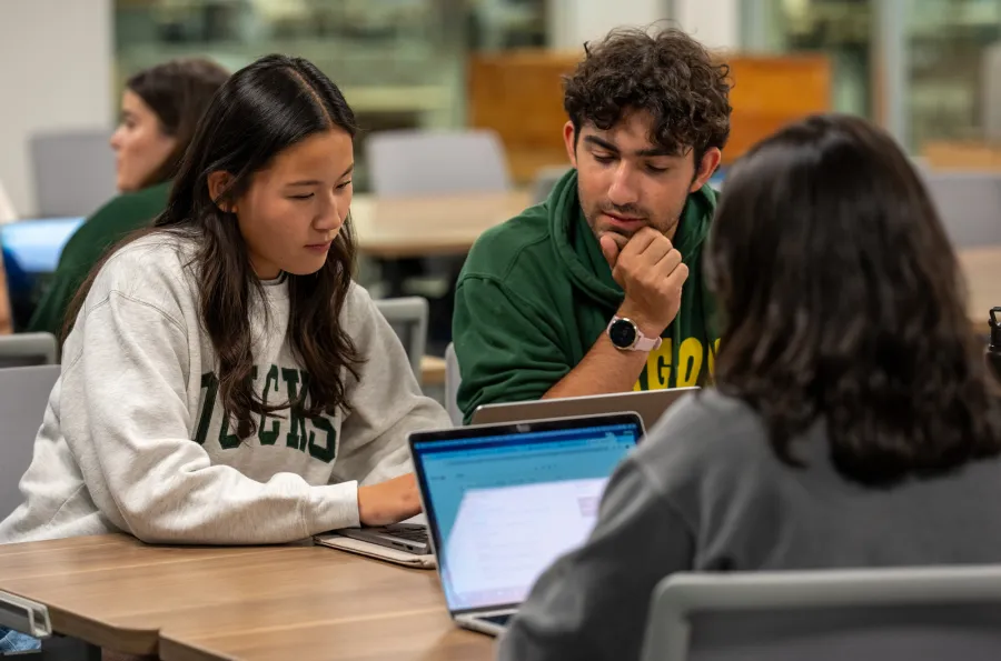 Three students sitting at a table looking at laptops