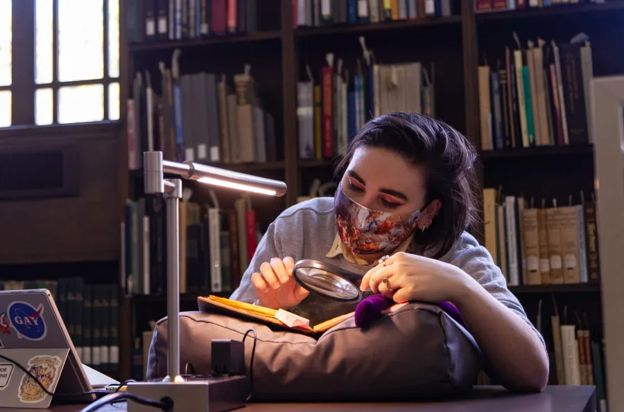 A researcher looking at a book with a magnifying glass