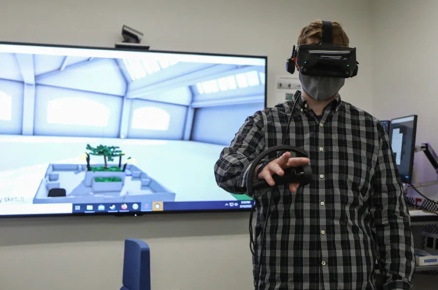 A person in front of a screen with virtual reality goggles on