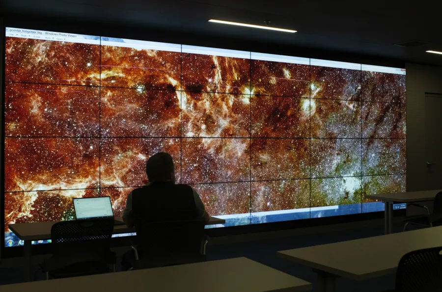 silhouette of a person looking at an image of space on the visualization lab screen