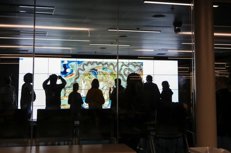 the silhouette of a group of people in front of a large screen