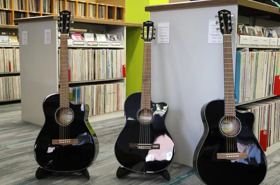 three upright guitars in front of library shelving