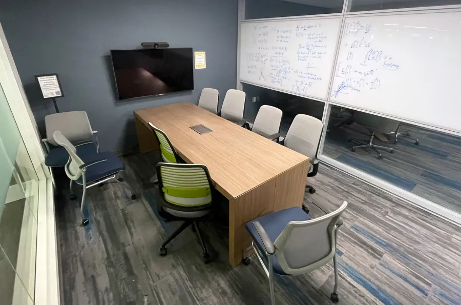 empty collaboration room with a table, screen, and white board