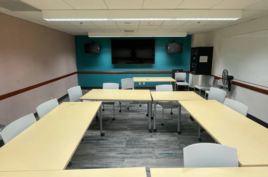 empty tables in a classroom with a screen on the far wall