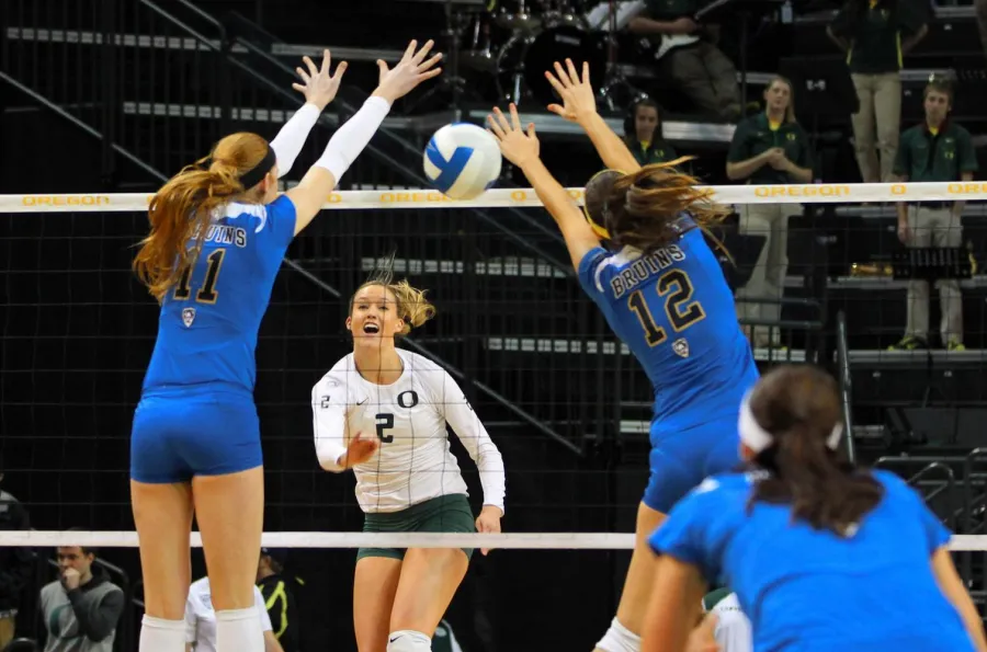 UO volleyball player Alaina Bergsma watching as her shot splits a pair of blockers during a match against UCLA in 2012.