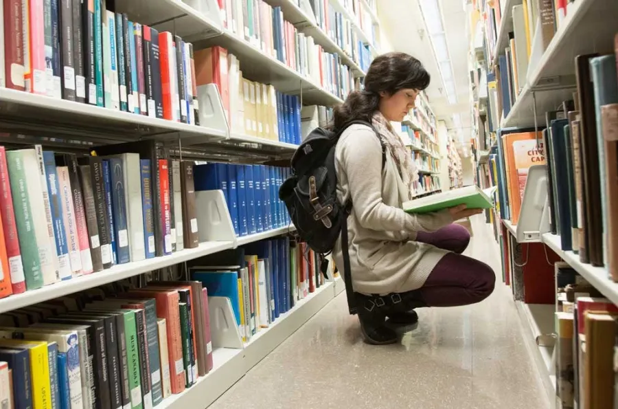 Student browsing books in the library stacks. 