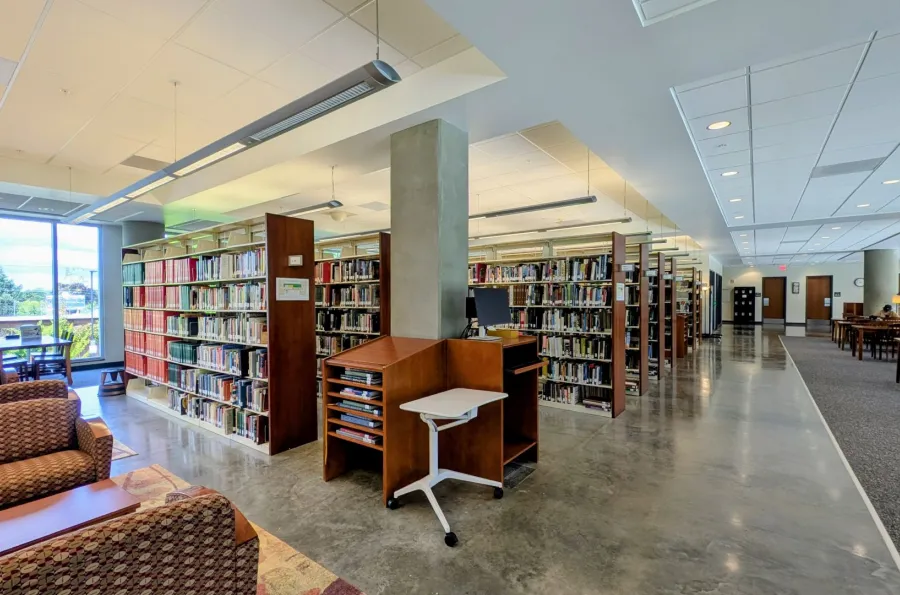 Library shelving with books, study tables, and lounge seating