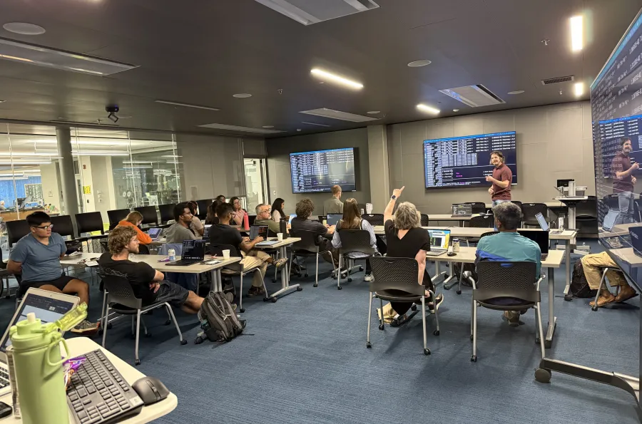 Standing at the front of a classroom, William Winter of RACS leads an HPC workshop session.