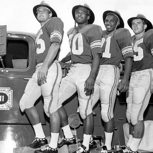"The Firehouse Four," members of the 1963 University of Oregon football team's offensive backfield, posing beside a fire truck wearing fire helmets.