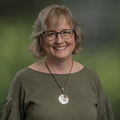 Portrait photo of Jolinda Smith standing against a green background.